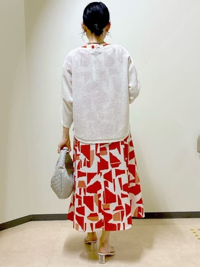 ベージュ系のニット/セーター、オレンジ系のワンピース、ベージュ系のハンドバッグを着用したレディースの夏コーディネートの3枚目の写真