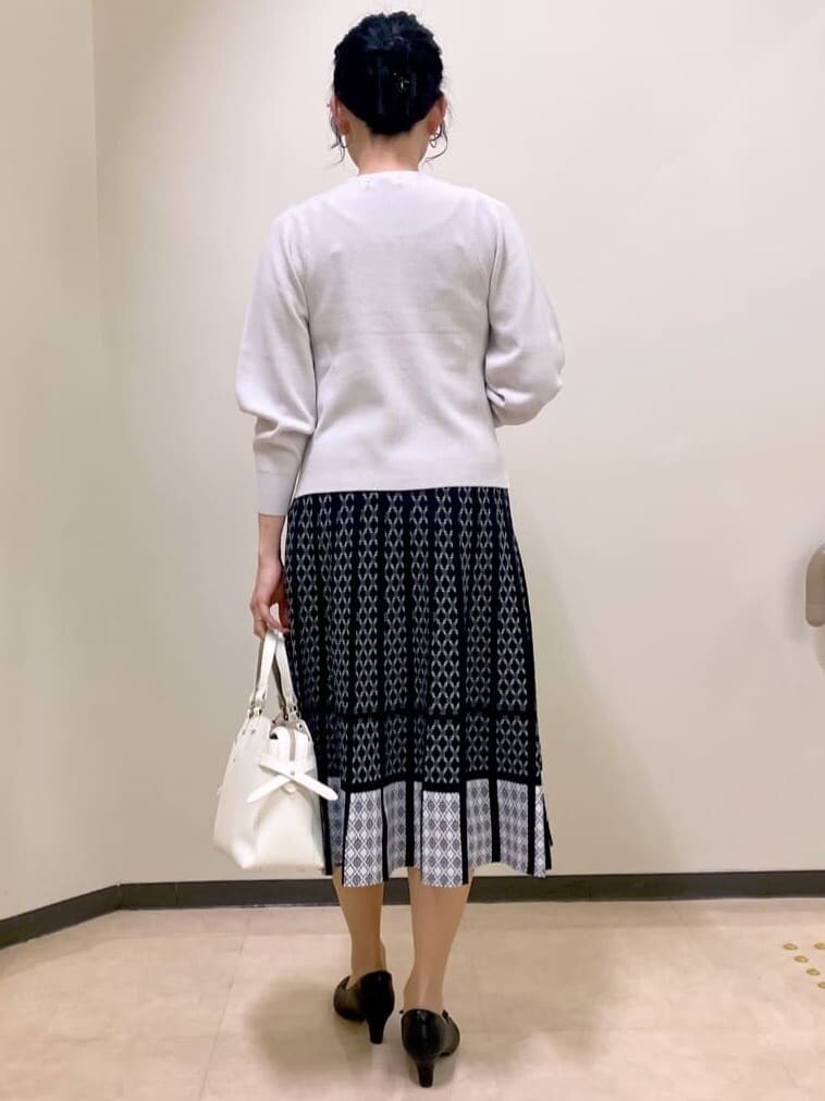 グレー系のニット/セーター、ブルー系のスカート、ホワイト系のトートバッグを着用したレディースの冬コーディネートの3枚目の写真