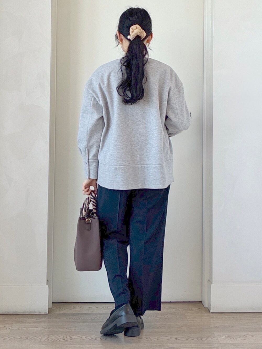 ブルー系のその他パンツ、ブラウン系のトートバッグ、シルバー系のネックレスを着用したレディースの秋コーディネートの3枚目の写真