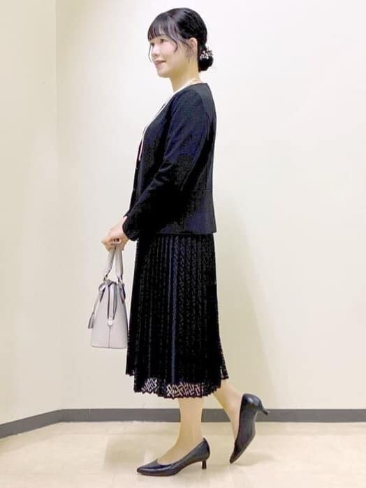 ブラック系のノーカラージャケット、ブラック系のワンピース、ベージュ系のハンドバッグを着用したレディースの冬コーディネートの2枚目の写真