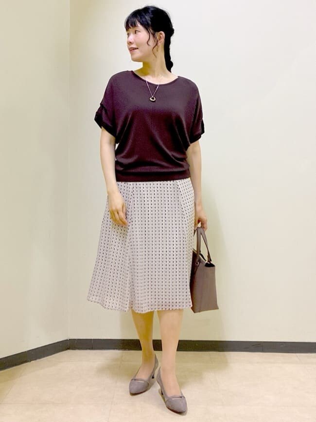 レッド系のTシャツ/カットソー、ベージュ系のスカート、ブラウン系のニット/セーターを着用したレディースの秋コーディネートの9枚目の写真