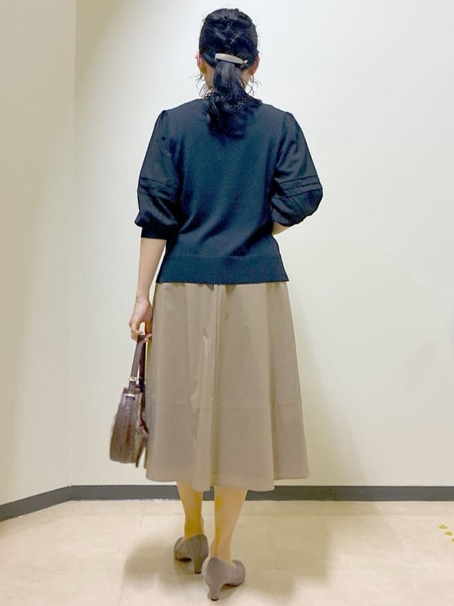 ブルー系のTシャツ/カットソー、イエロー系のスカート、ブラック系のニット/セーターを着用したレディースの秋コーディネートの3枚目の写真