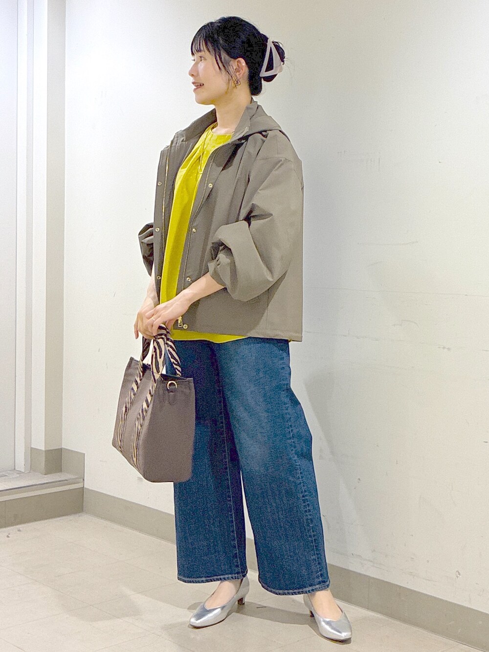 グリーン系のブルゾン、イエロー系のシャツ/ブラウス、ブルー系のデニムパンツを着用したレディースの秋コーディネートの6枚目の写真