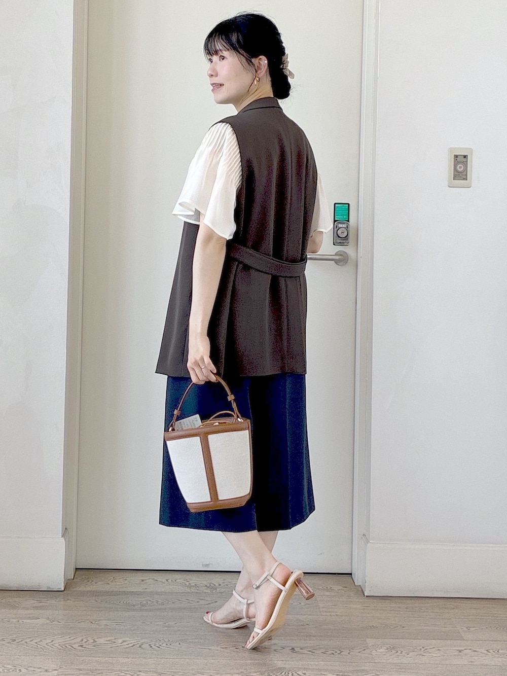 ホワイト系のシャツ/ブラウス、ブラック系のタンクトップ、ブラウン系のベストを着用したレディースの夏コーディネートの4枚目の写真