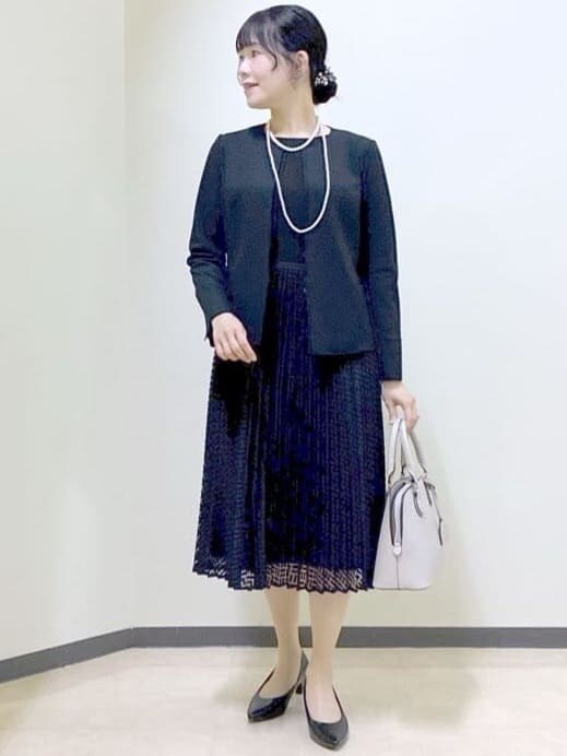 ブラック系のノーカラージャケット、ブラック系のワンピース、ベージュ系のハンドバッグを着用したレディースの冬コーディネートの5枚目の写真