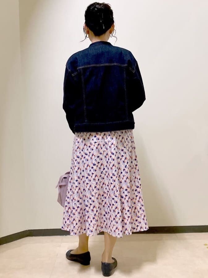 ブルー系のデニムジャケット、ホワイト系のニット/セーター、オレンジ系のスカートを着用したレディースの春コーディネートの3枚目の写真