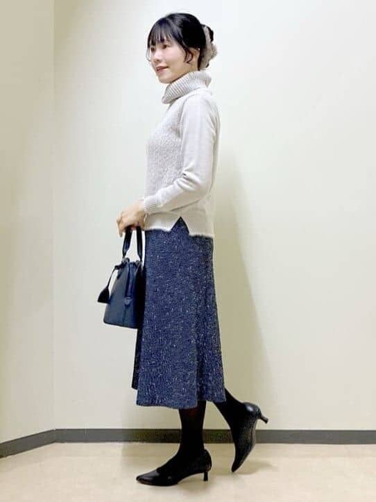 グレー系のニット/セーター、ブルー系のスカート、ブルー系のハンドバッグを着用したレディースの冬コーディネートの2枚目の写真