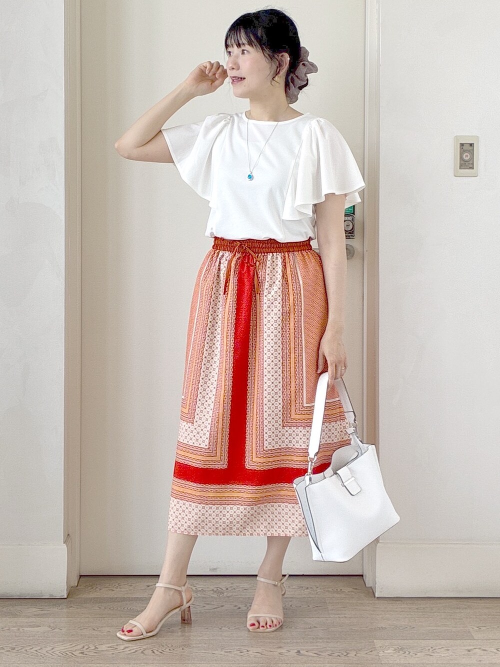 ホワイト系のTシャツ/カットソー、オレンジ系のスカート、ホワイト系のトートバッグを着用したレディースの夏コーディネートの10枚目の写真