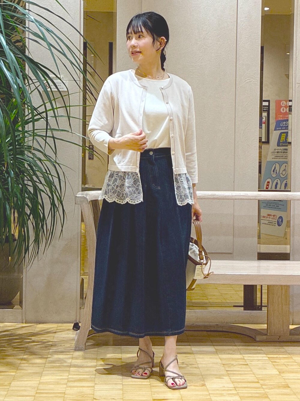 グレー系のカーディガン/ボレロ、ホワイト系のTシャツ/カットソー、ブルー系のデニムスカートを着用したレディースの秋コーディネートの5枚目の写真