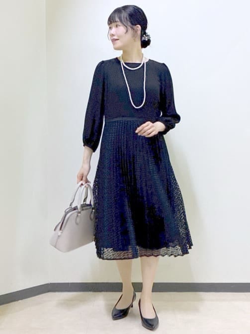 ブラック系のノーカラージャケット、ブラック系のワンピース、ベージュ系のハンドバッグを着用したレディースの冬コーディネートの9枚目の写真