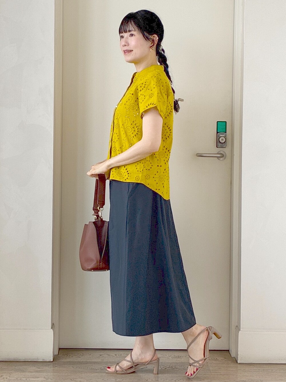 イエロー系のシャツ/ブラウス、ベージュ系のタンクトップ、ホワイト系のカーディガン/ボレロを着用したレディースの夏コーディネートの2枚目の写真