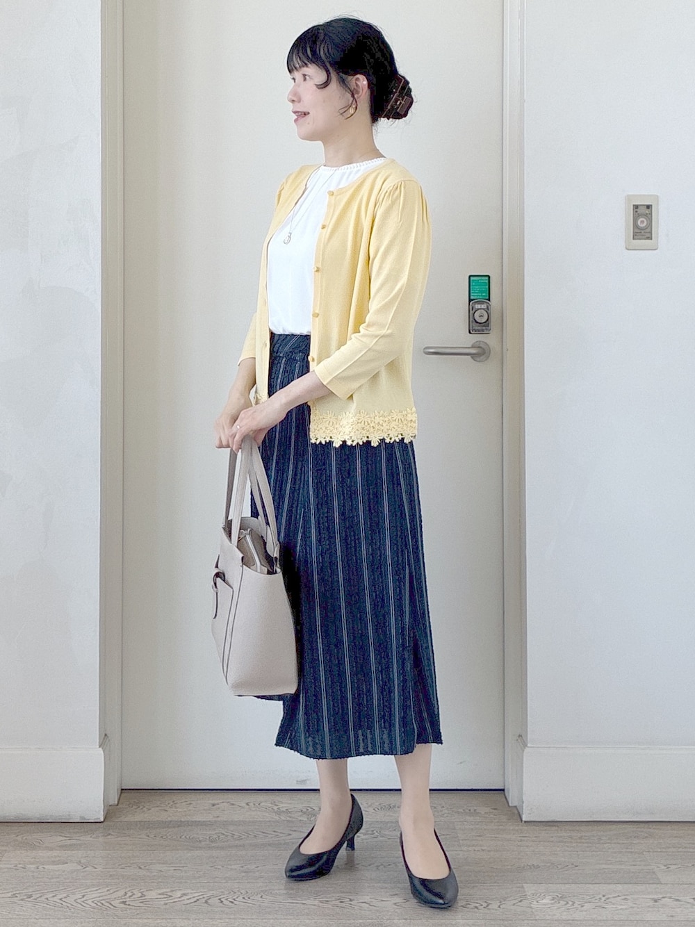 イエロー系のカーディガン/ボレロ、ホワイト系のシャツ/ブラウス、ブルー系のスカートを着用したレディースの春コーディネートの7枚目の写真
