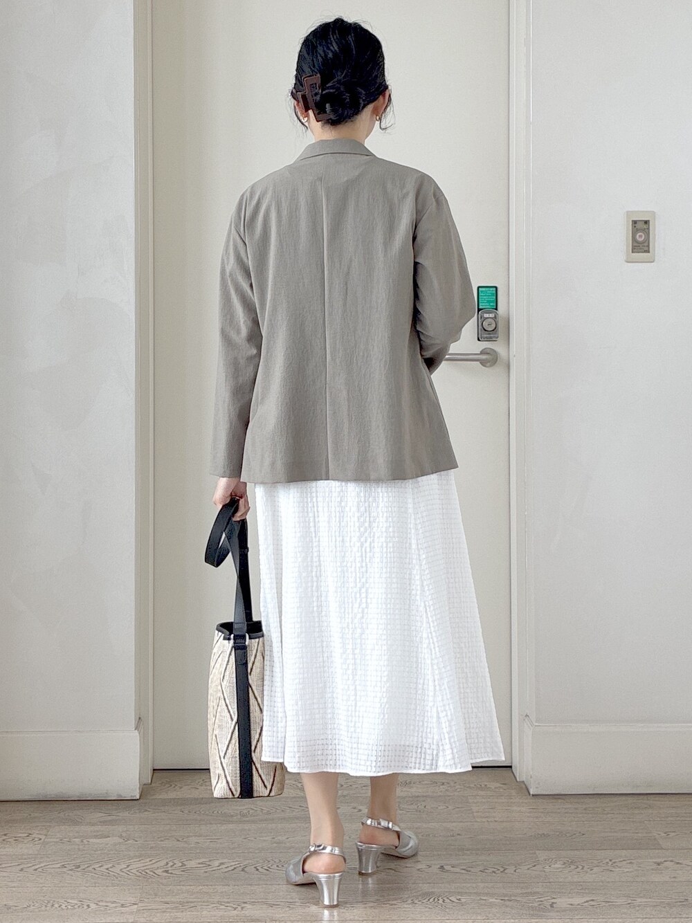 ベージュ系のショルダーバッグ、ホワイト系のスカート、ブラック系のTシャツ/カットソーを着用したレディースの春コーディネートの3枚目の写真
