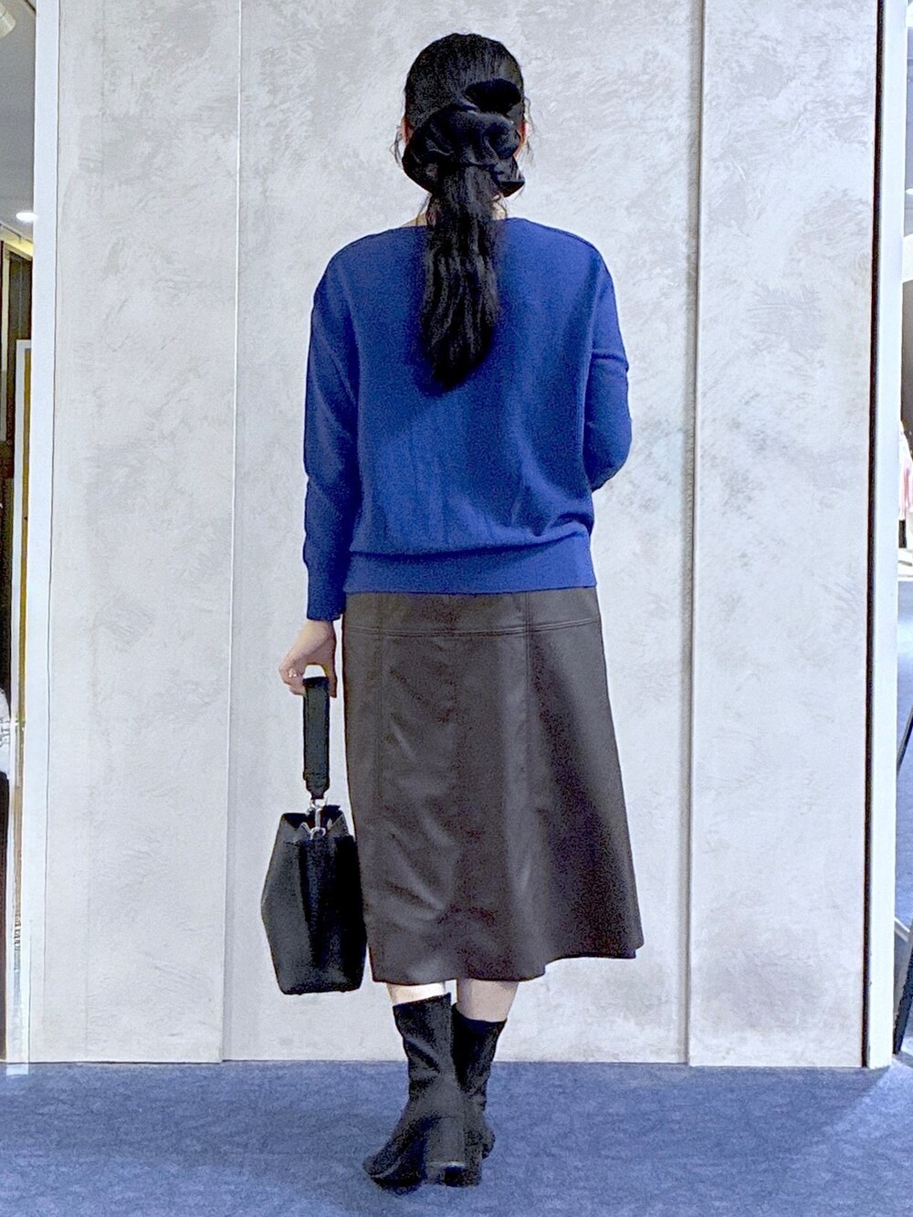 ブルー系のニット/セーター、ブラック系のブルゾン、ブラック系のトートバッグを着用したレディースの秋コーディネートの5枚目の写真