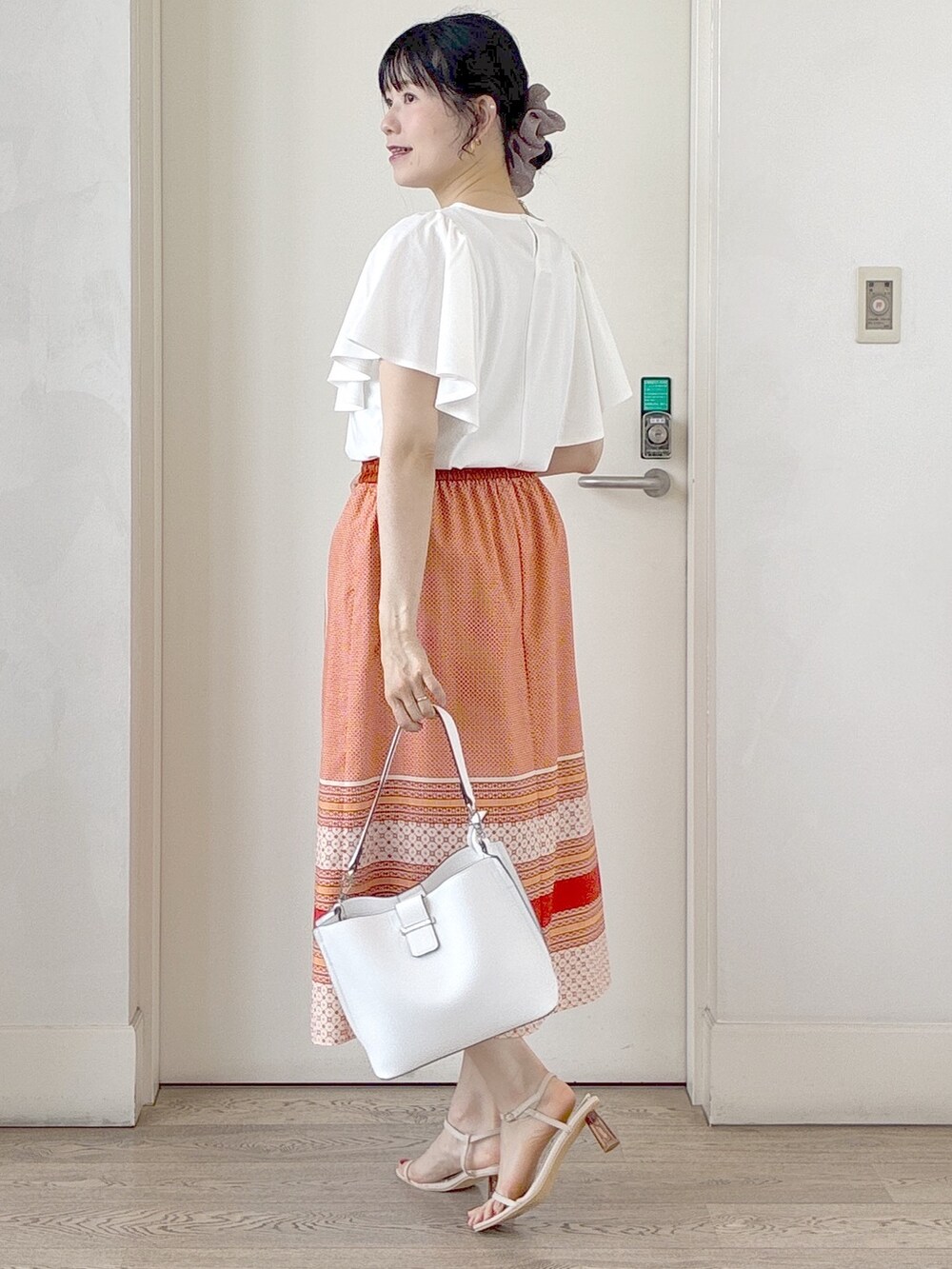 ホワイト系のTシャツ/カットソー、オレンジ系のスカート、ホワイト系のトートバッグを着用したレディースの夏コーディネートの7枚目の写真