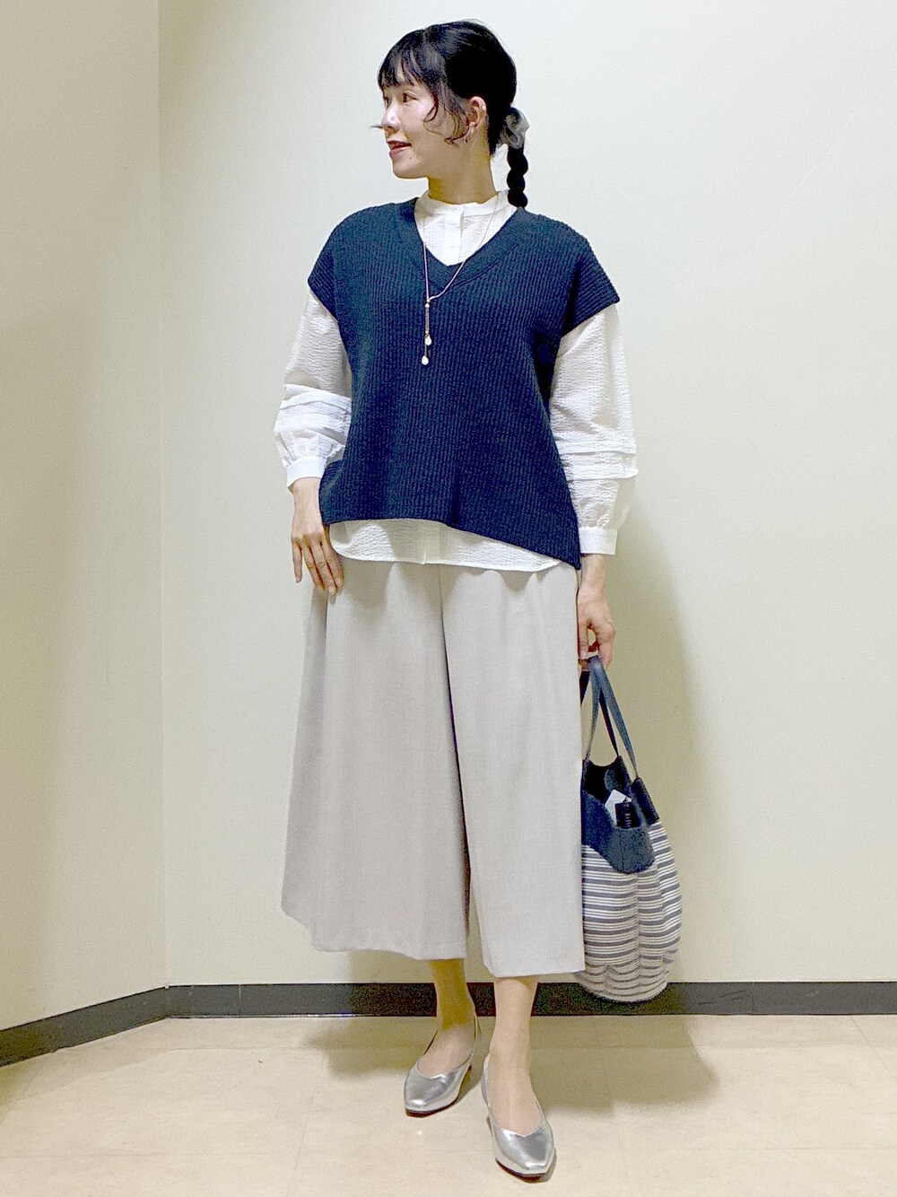 ブルー系のニット/セーター、ホワイト系のシャツ/ブラウス、ベージュ系のその他パンツを着用したレディースの春コーディネートの7枚目の写真