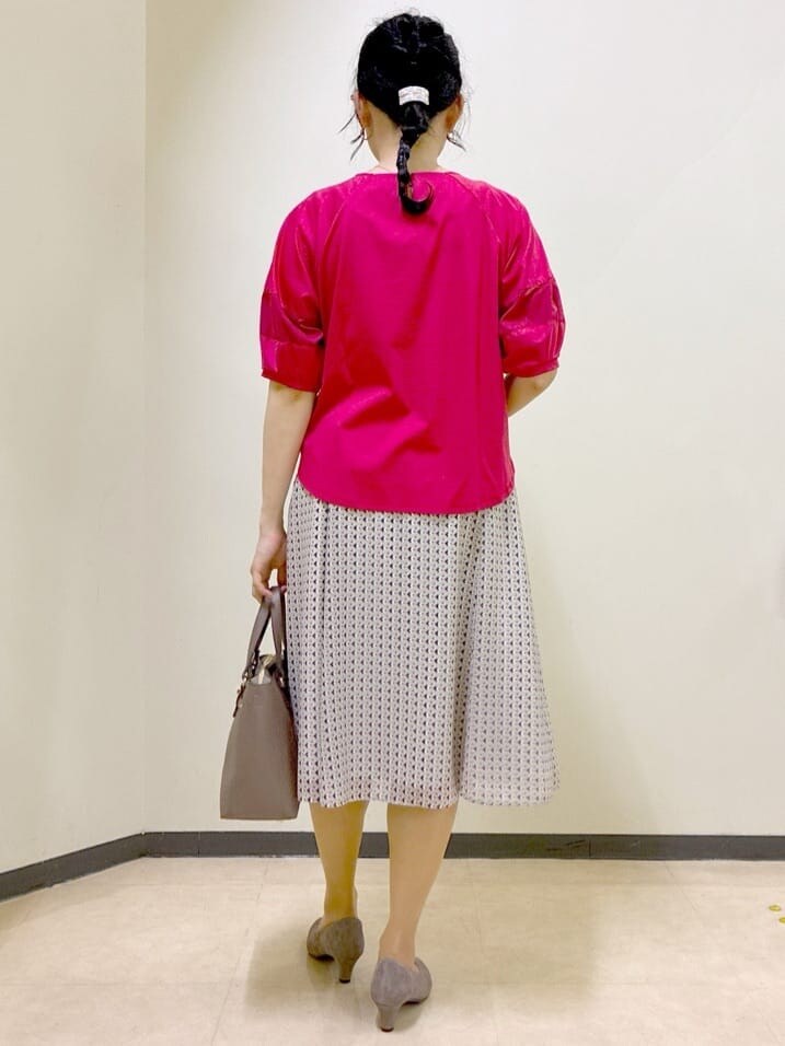レッド系のTシャツ/カットソー、ベージュ系のスカート、ブラウン系のニット/セーターを着用したレディースの秋コーディネートの3枚目の写真