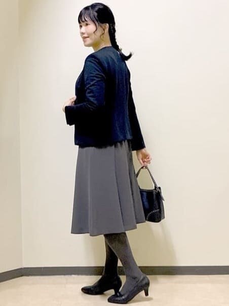 ブルー系のノーカラージャケット、ブルー系のニット/セーター、グレー系のスカートを着用したレディースの秋コーディネートの2枚目の写真