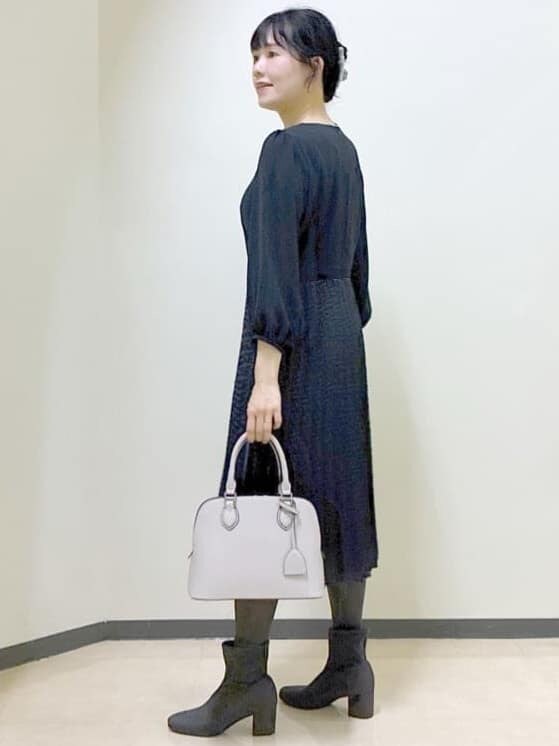 ブルー系のワンピース、グレー系のチェスターコート、ベージュ系のハンドバッグを着用したレディースの冬コーディネートの4枚目の写真