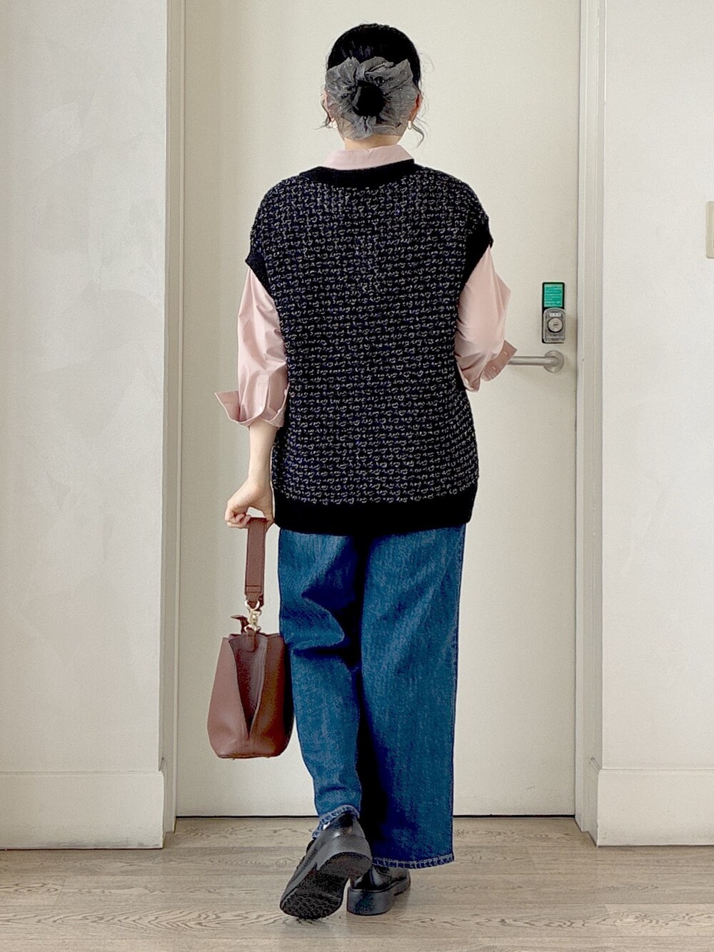 ブラック系のニット/セーター、ピンク系のシャツ/ブラウス、ブルー系のデニムパンツを着用したレディースの秋コーディネートの3枚目の写真