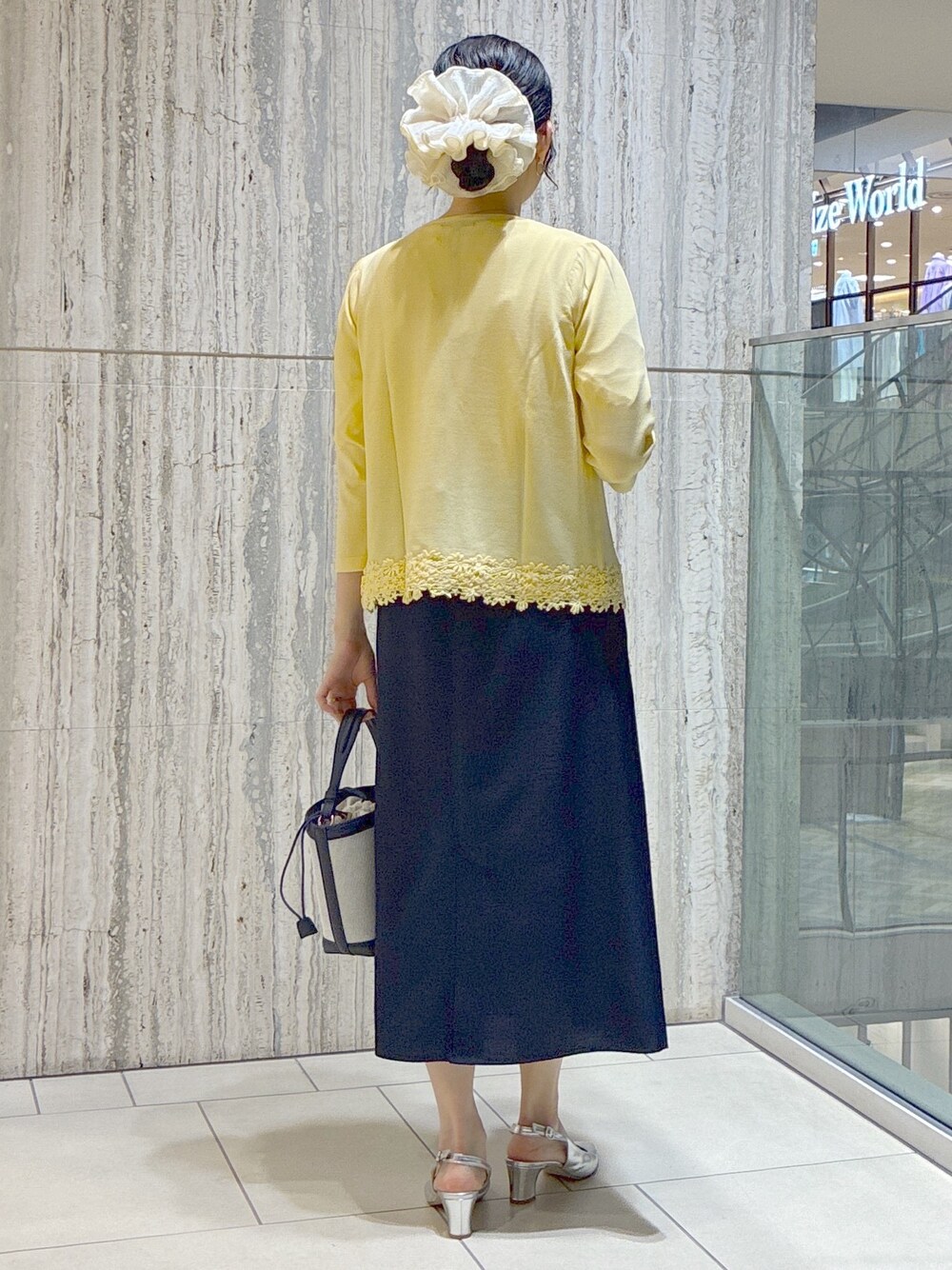 イエロー系のカーディガン/ボレロ、ホワイト系のTシャツ/カットソー、ブルー系のスカートを着用したレディースの夏コーディネートの3枚目の写真