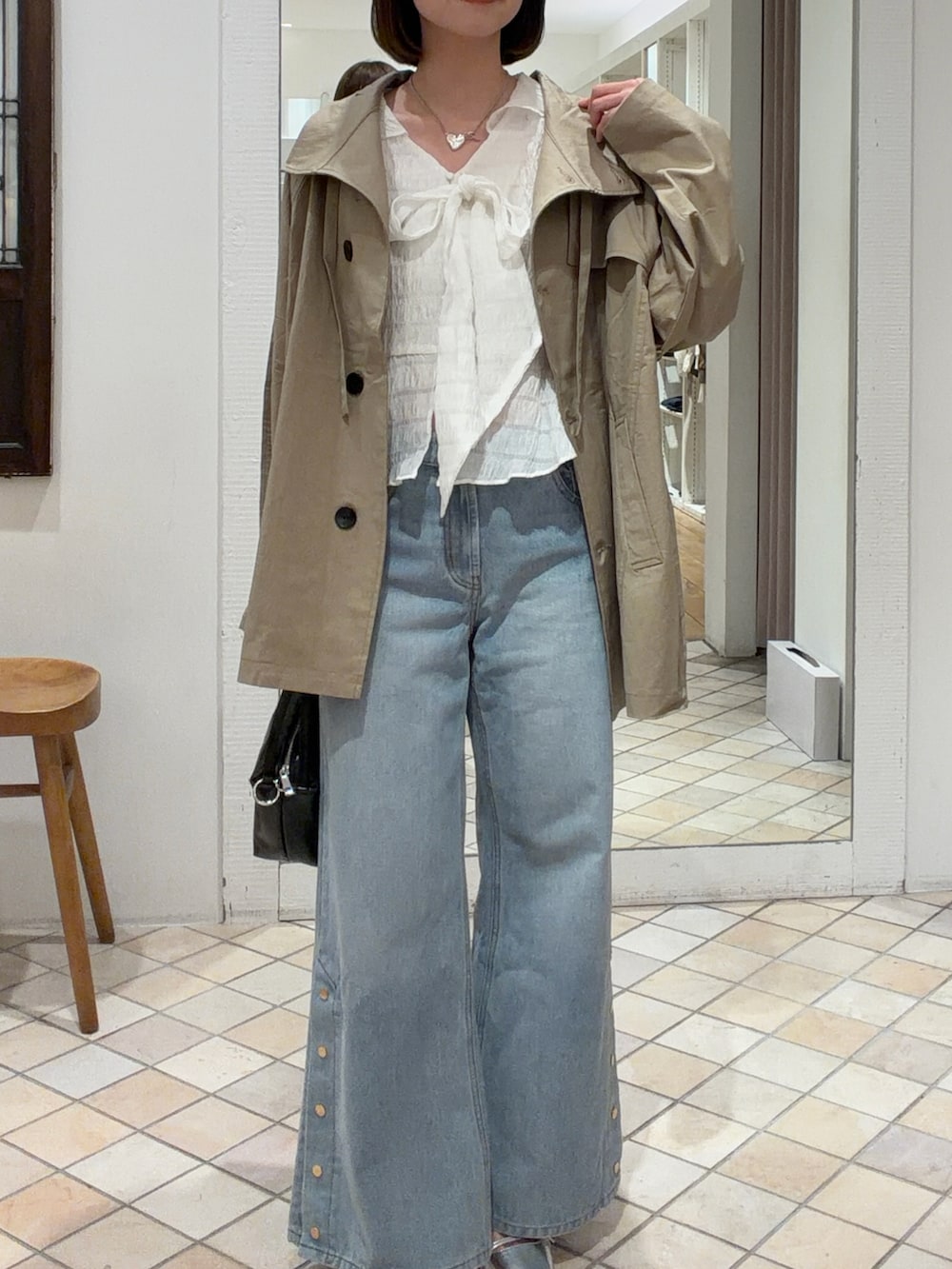 ベージュ系のトレンチコート、ホワイト系のシャツ/ブラウス、ブラック系のトートバッグを着用したレディースの春コーディネートの2枚目の写真