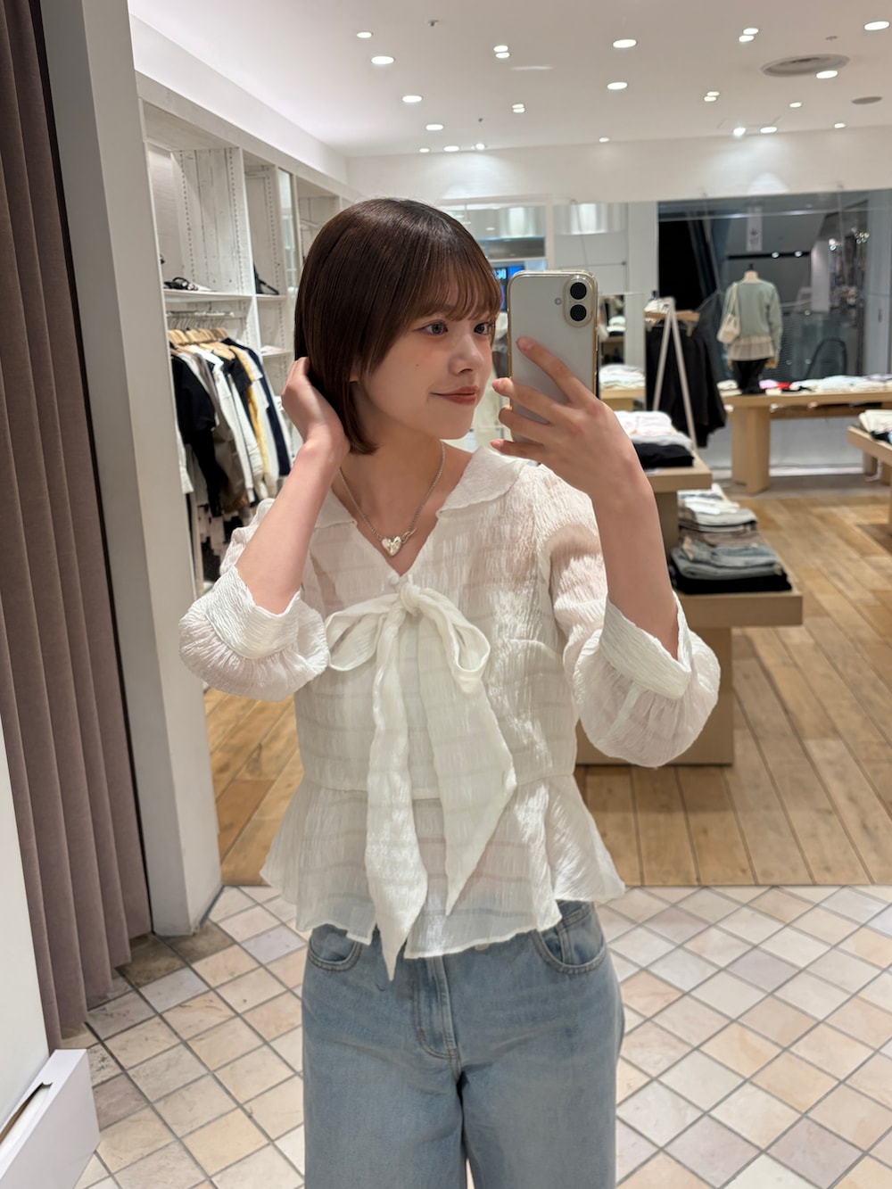 ベージュ系のトレンチコート、ホワイト系のシャツ/ブラウス、ブラック系のトートバッグを着用したレディースの春コーディネートの3枚目の写真