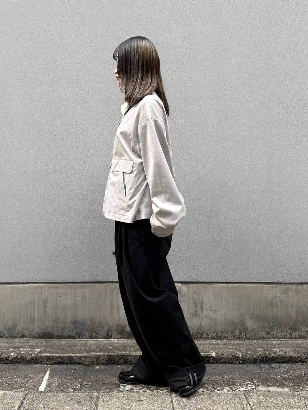 グレー系のブルゾン、ブラック系のチノパンツを着用したレディースの春コーディネートの4枚目の写真