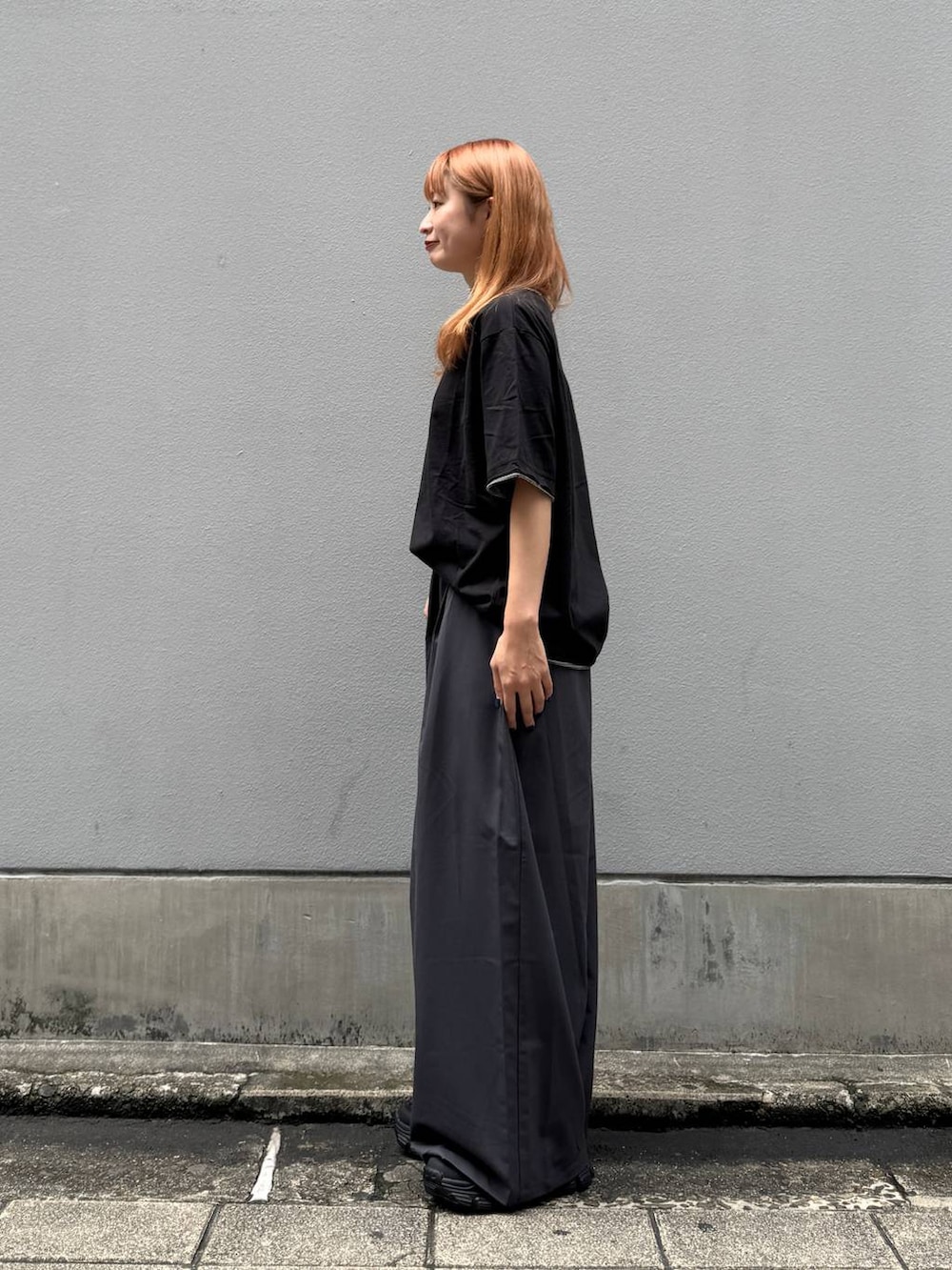 ブラック系のTシャツ/カットソー、グレー系のスラックス、ブラック系のサンダルを着用したレディースの夏コーディネートの5枚目の写真
