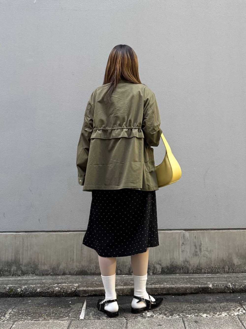 ブラック系のパンプス、イエロー系のショルダーバッグ、ブラック系のワンピースを着用したレディースの春コーディネートの6枚目の写真