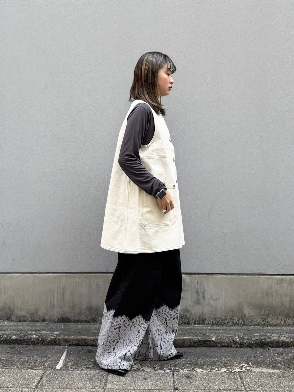 ブラック系のパンプス、ホワイト系のワンピース、ブラック系のデニムパンツを着用したレディースの春コーディネートの6枚目の写真