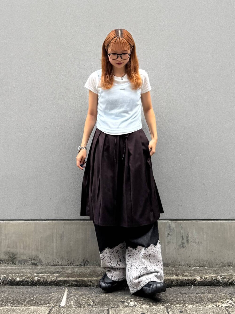 ブラウン系のスカート、ブラック系のデニムパンツ、ホワイト系のTシャツ/カットソーを着用したレディースの秋コーディネートの3枚目の写真