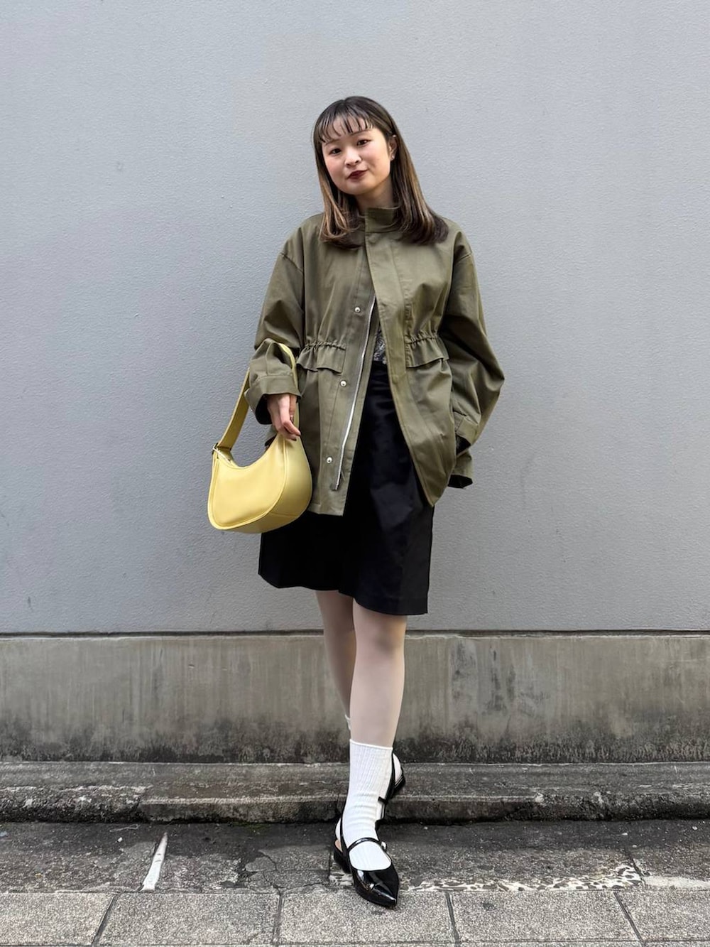 ブラック系のパンプス、ブラック系のスラックス、イエロー系のショルダーバッグを着用したレディースの春コーディネートの3枚目の写真