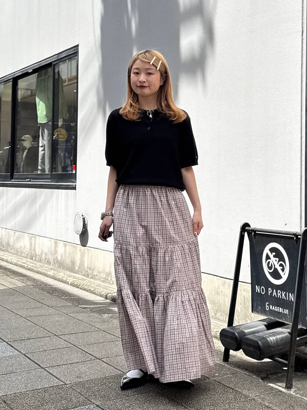 ブラック系のパンプス、ブラック系のポロシャツ、ベージュ系のスカートを着用したレディースの春コーディネートの3枚目の写真