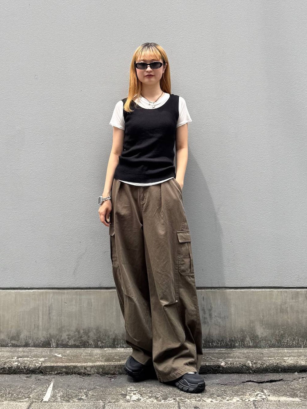 グリーン系のカーゴパンツ、ブラック系のタンクトップ、ブラック系のサンダルを着用したレディースの夏コーディネートの2枚目の写真