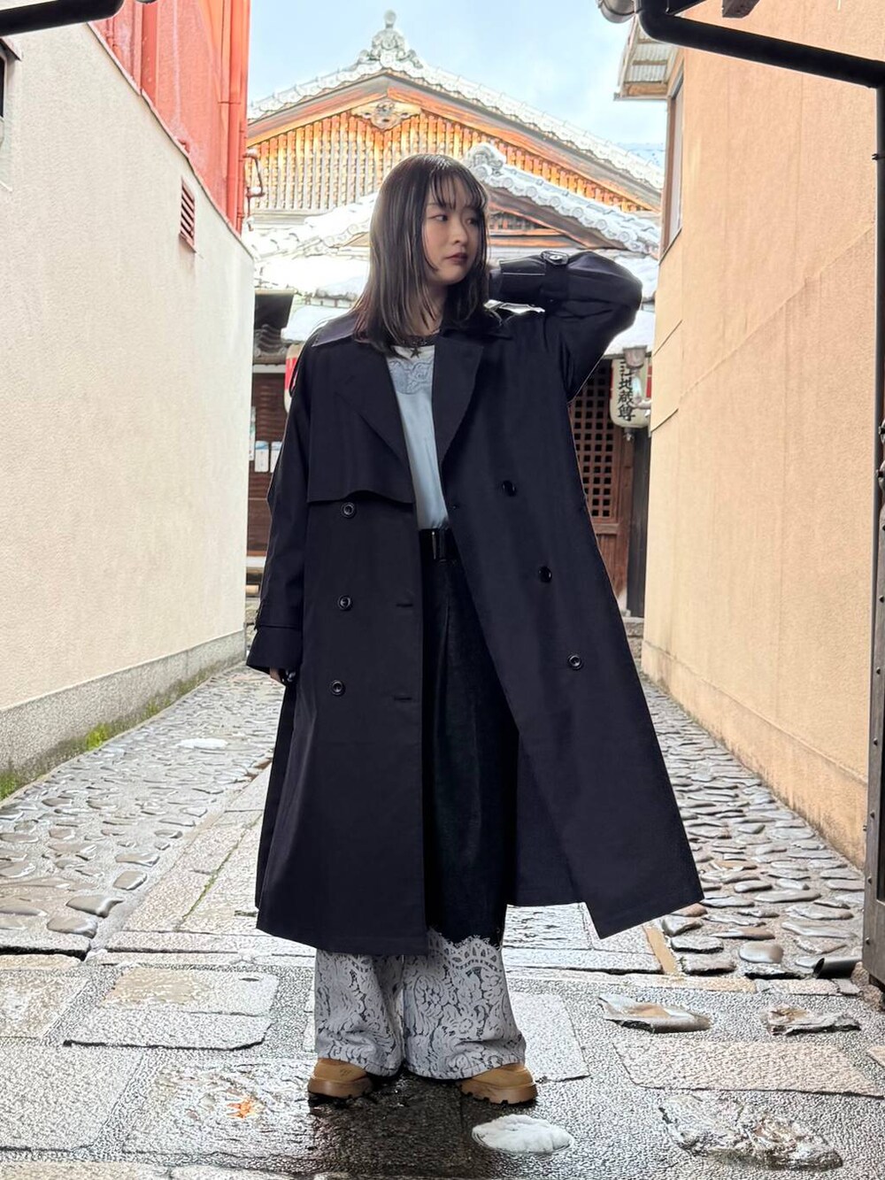 ブルー系のトレンチコート、ブラック系のデニムパンツ、ブルー系のキャミソールを着用したレディースの春コーディネートの3枚目の写真