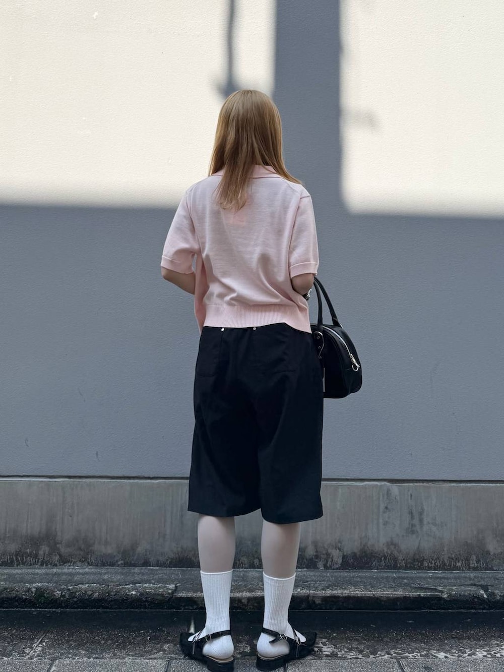 ブラック系のパンプス、ブラック系のスラックス、ブラック系のボストンバッグを着用したレディースの春コーディネートの6枚目の写真