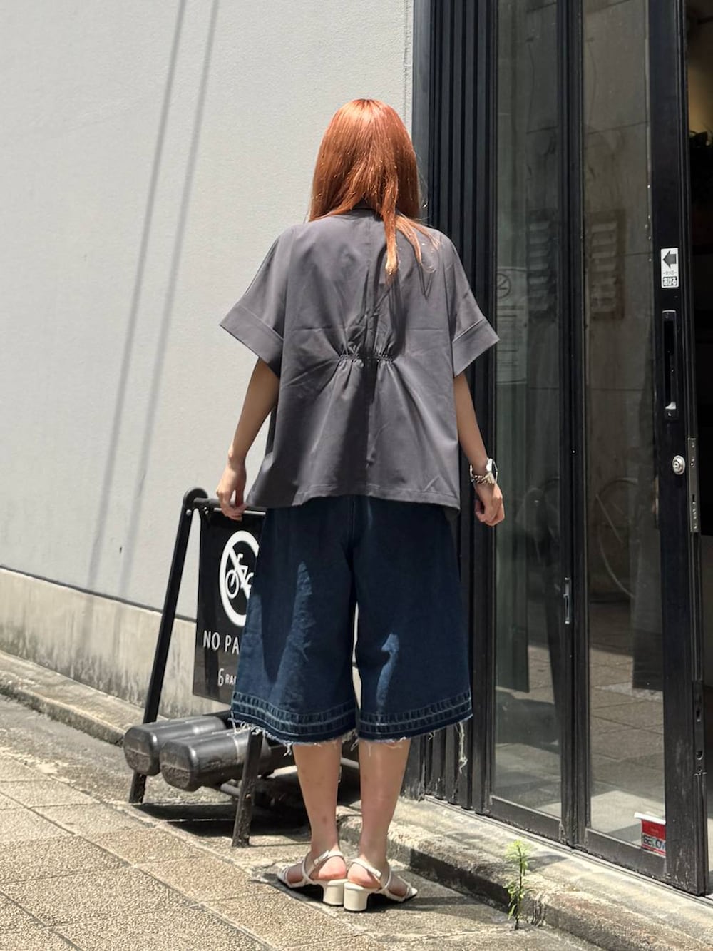 ブルー系のデニムパンツ、グレー系のテーラードジャケット、ホワイト系のキャミソールを着用したレディースの夏コーディネートの5枚目の写真
