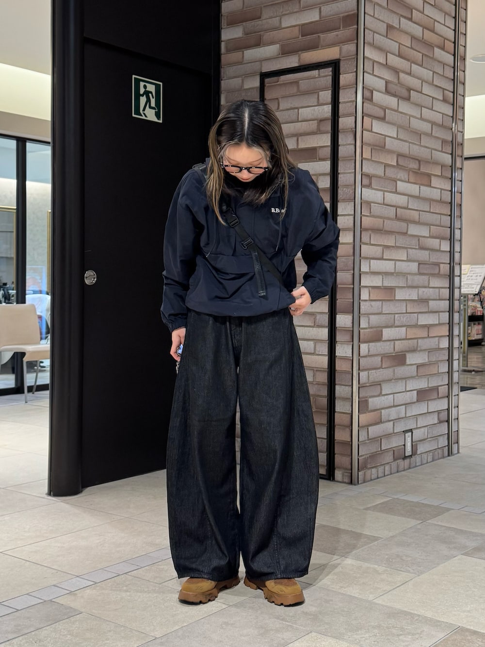 ブルー系のナイロンジャケット、ブラック系のデニムパンツ、ブラウン系のスニーカーを着用したレディースの春コーディネートの5枚目の写真