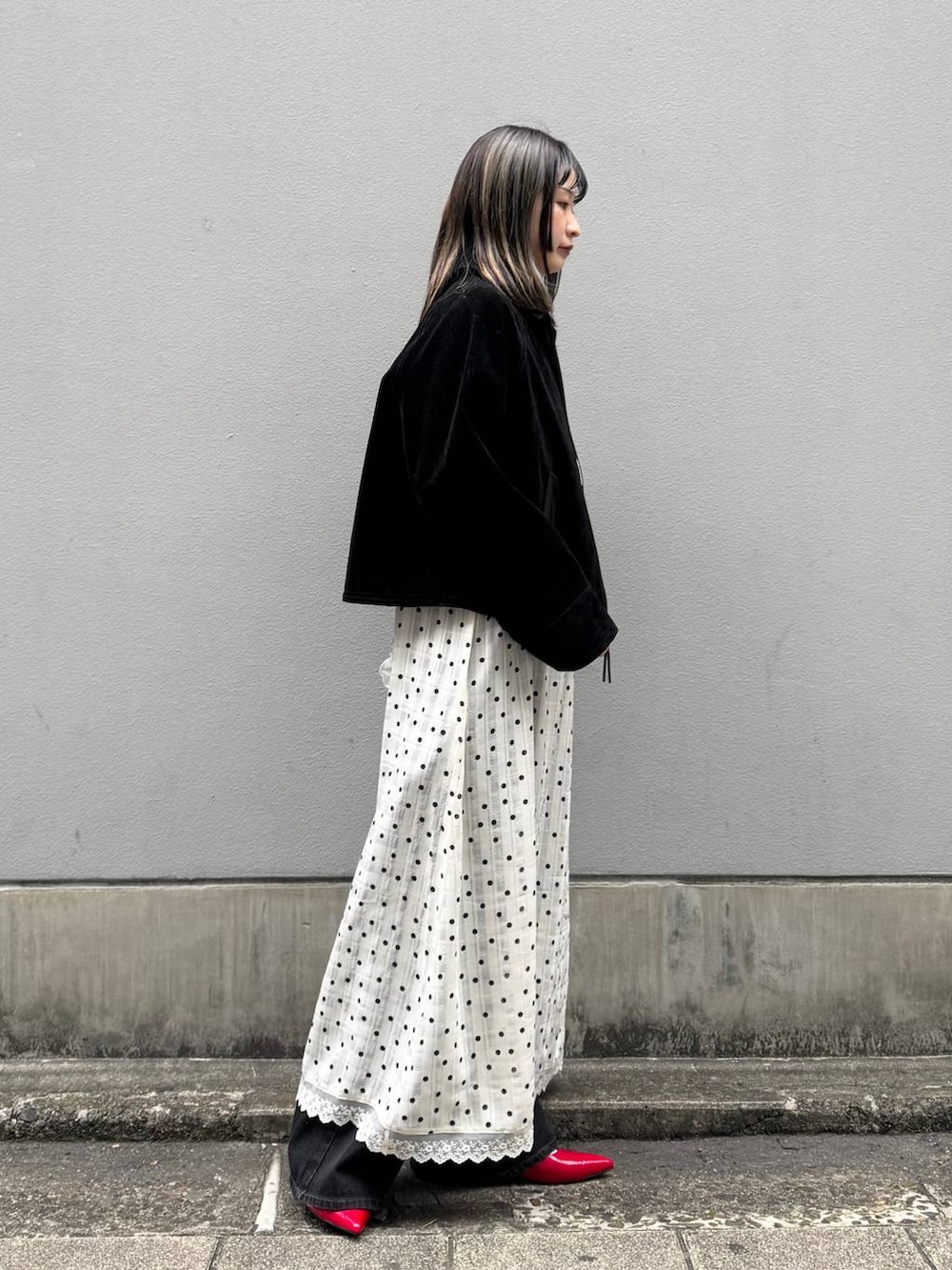 レッド系のパンプス、ブラック系のデニムパンツ、ブラック系のブルゾンを着用したレディースの春コーディネートの6枚目の写真