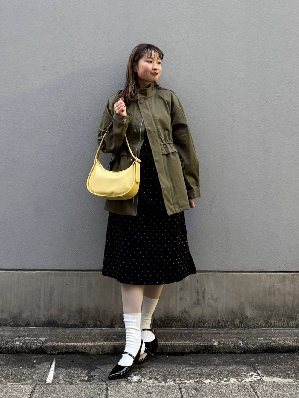 ブラック系のパンプス、イエロー系のショルダーバッグ、ブラック系のワンピースを着用したレディースの春コーディネートの3枚目の写真