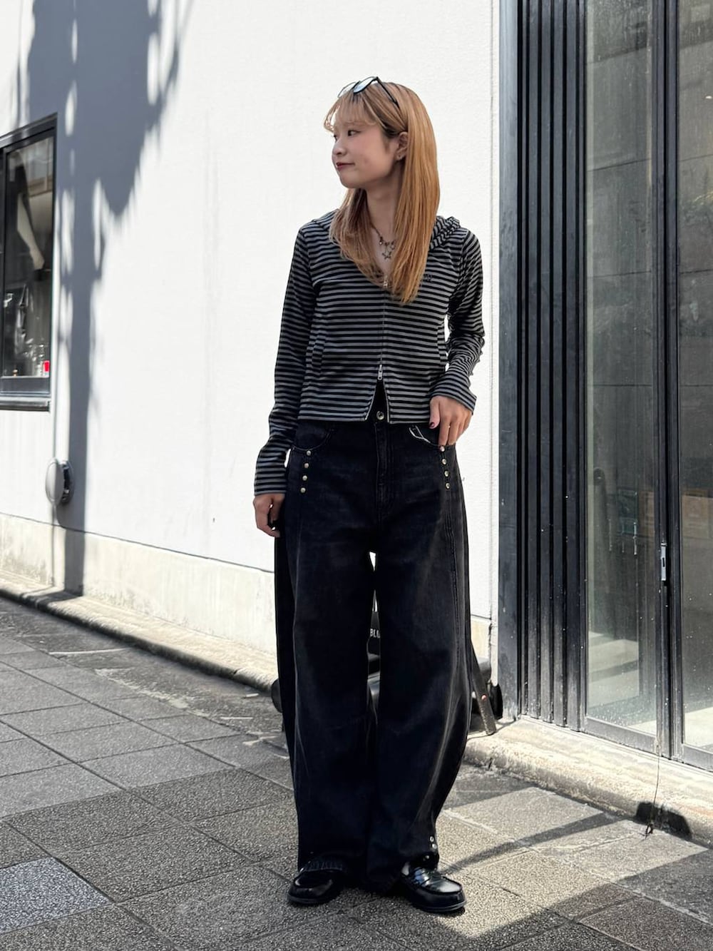 ブラック系のパーカー、グレー系のデニムパンツを着用したレディースの夏コーディネートの3枚目の写真