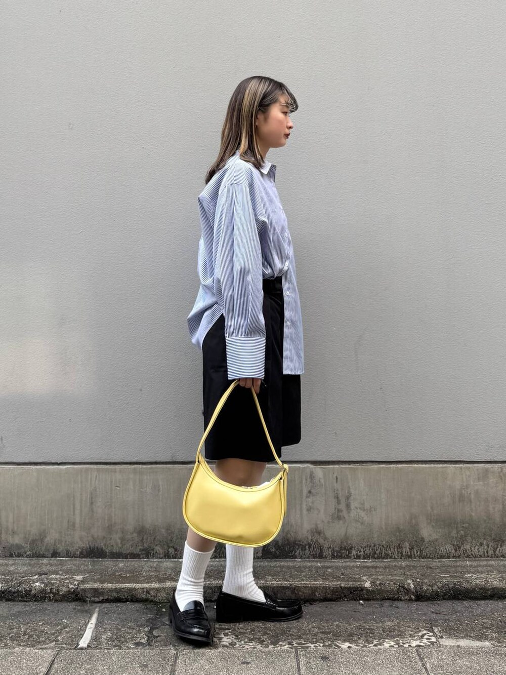 ブラック系のスラックス、イエロー系のショルダーバッグ、ブルー系のシャツ/ブラウスを着用したレディースの春コーディネートの6枚目の写真