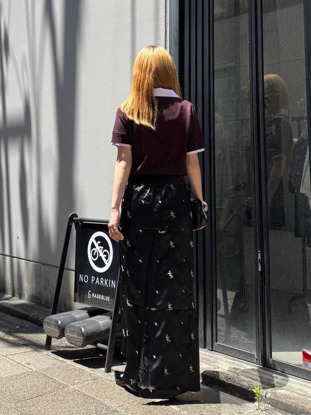 ブラック系のパンプス、ブラック系のスカート、ブラック系のショルダーバッグを着用したレディースの夏コーディネートの6枚目の写真