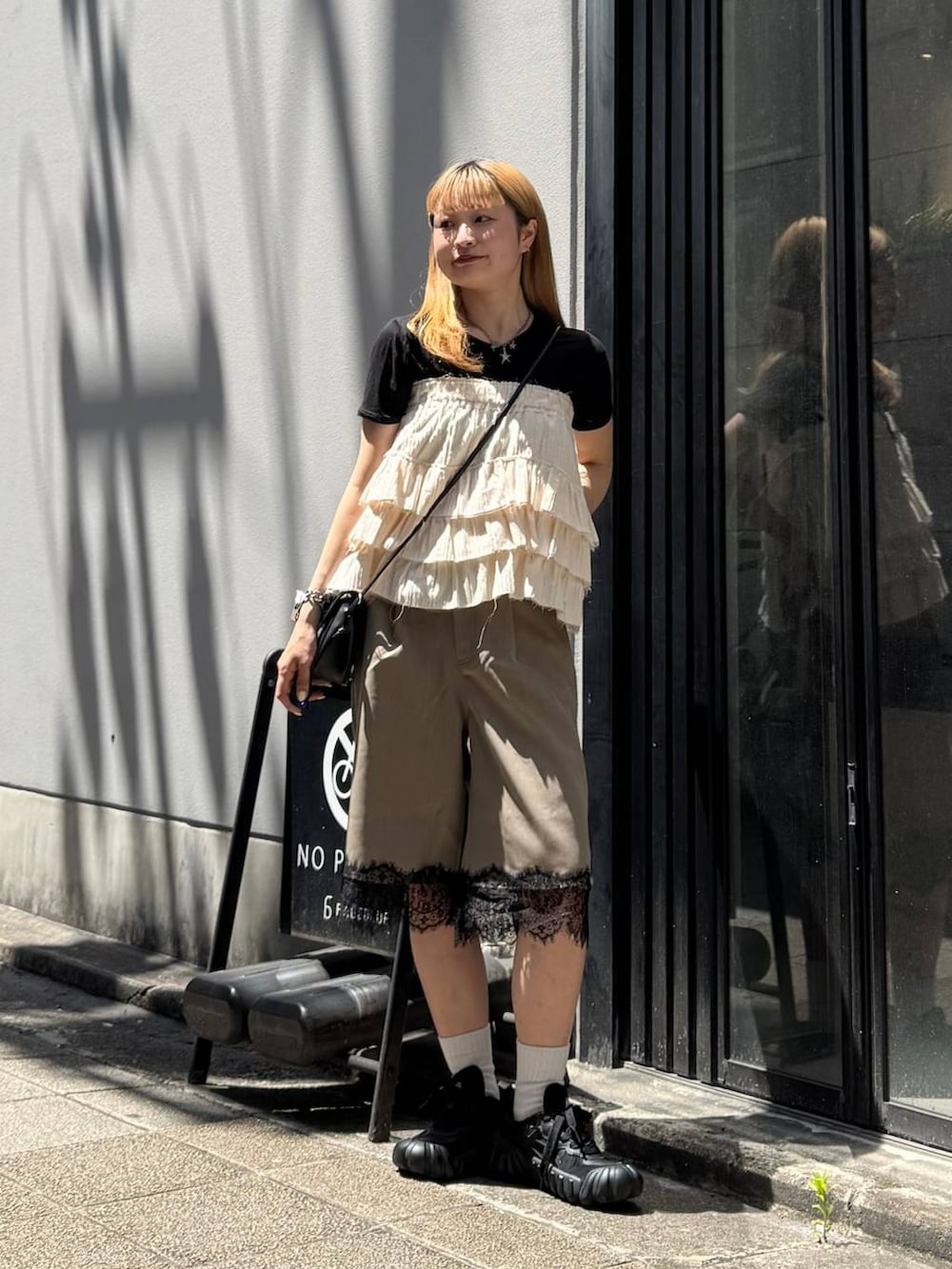 ブラック系のTシャツ/カットソー、ブラック系のショルダーバッグ、ブラウン系のスラックスを着用したレディースの夏コーディネートの3枚目の写真
