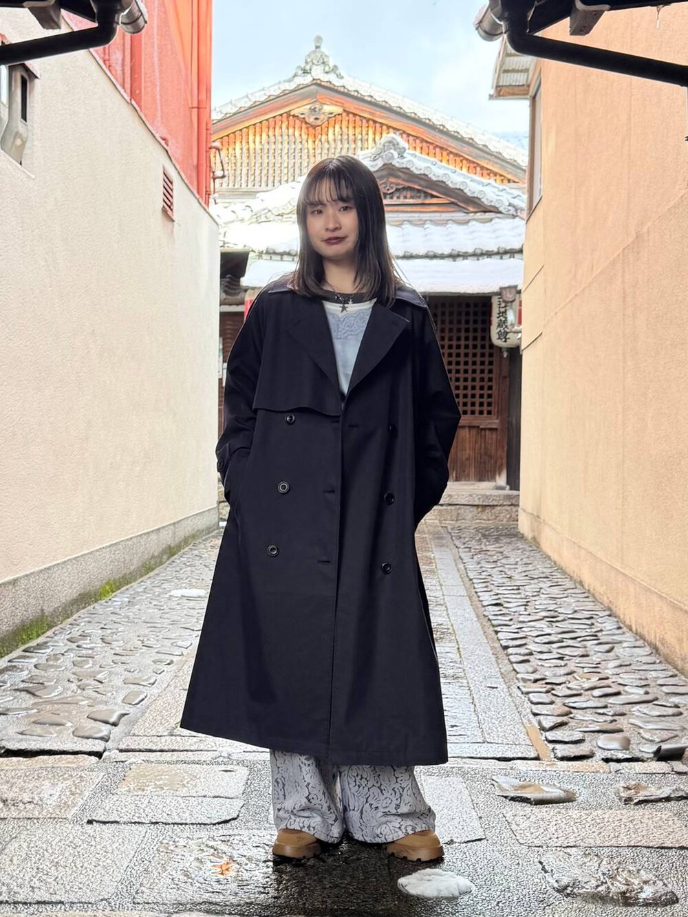 ブルー系のトレンチコート、ブラック系のデニムパンツ、ブルー系のキャミソールを着用したレディースの春コーディネートの2枚目の写真