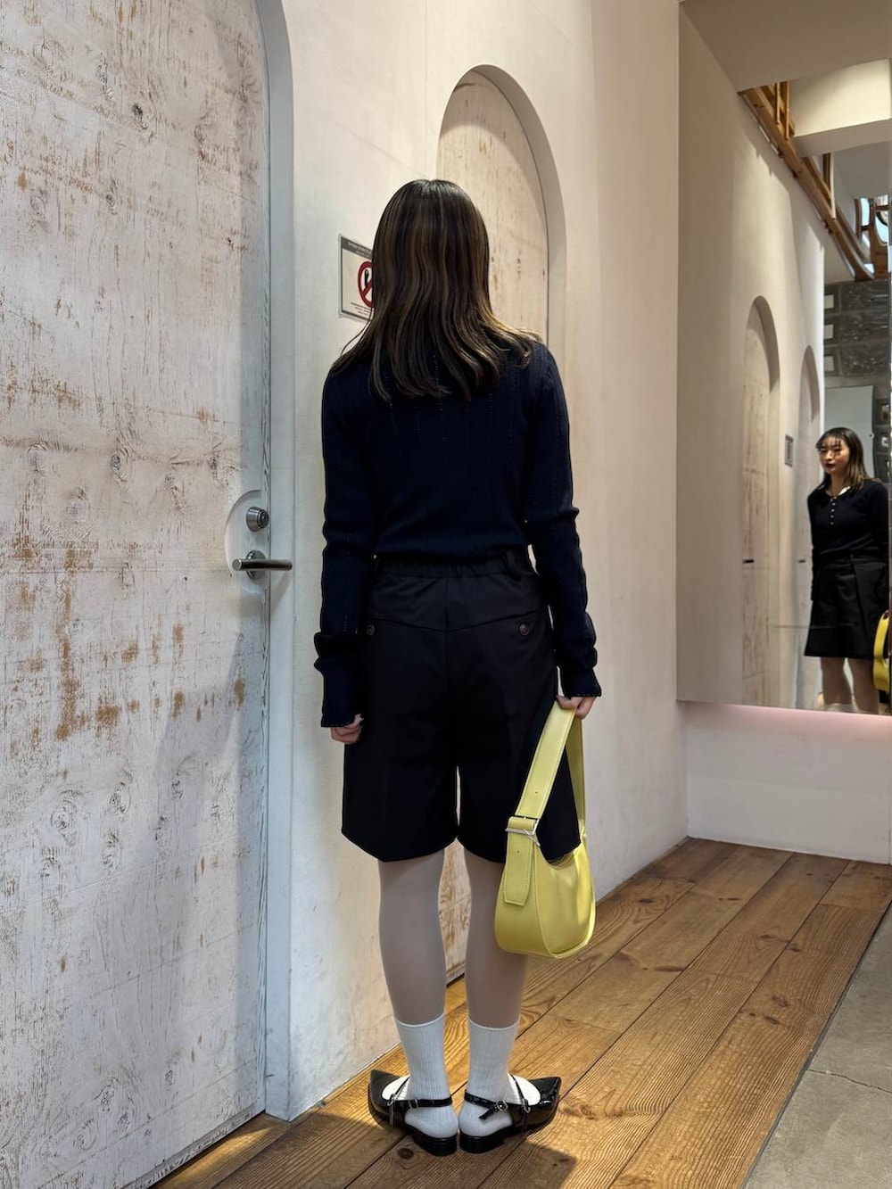 ブラック系のパンプス、ブラック系のスラックス、イエロー系のショルダーバッグを着用したレディースの春コーディネートの6枚目の写真