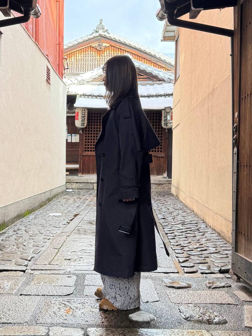 ブルー系のトレンチコート、ブラック系のデニムパンツ、ブルー系のキャミソールを着用したレディースの春コーディネートの4枚目の写真
