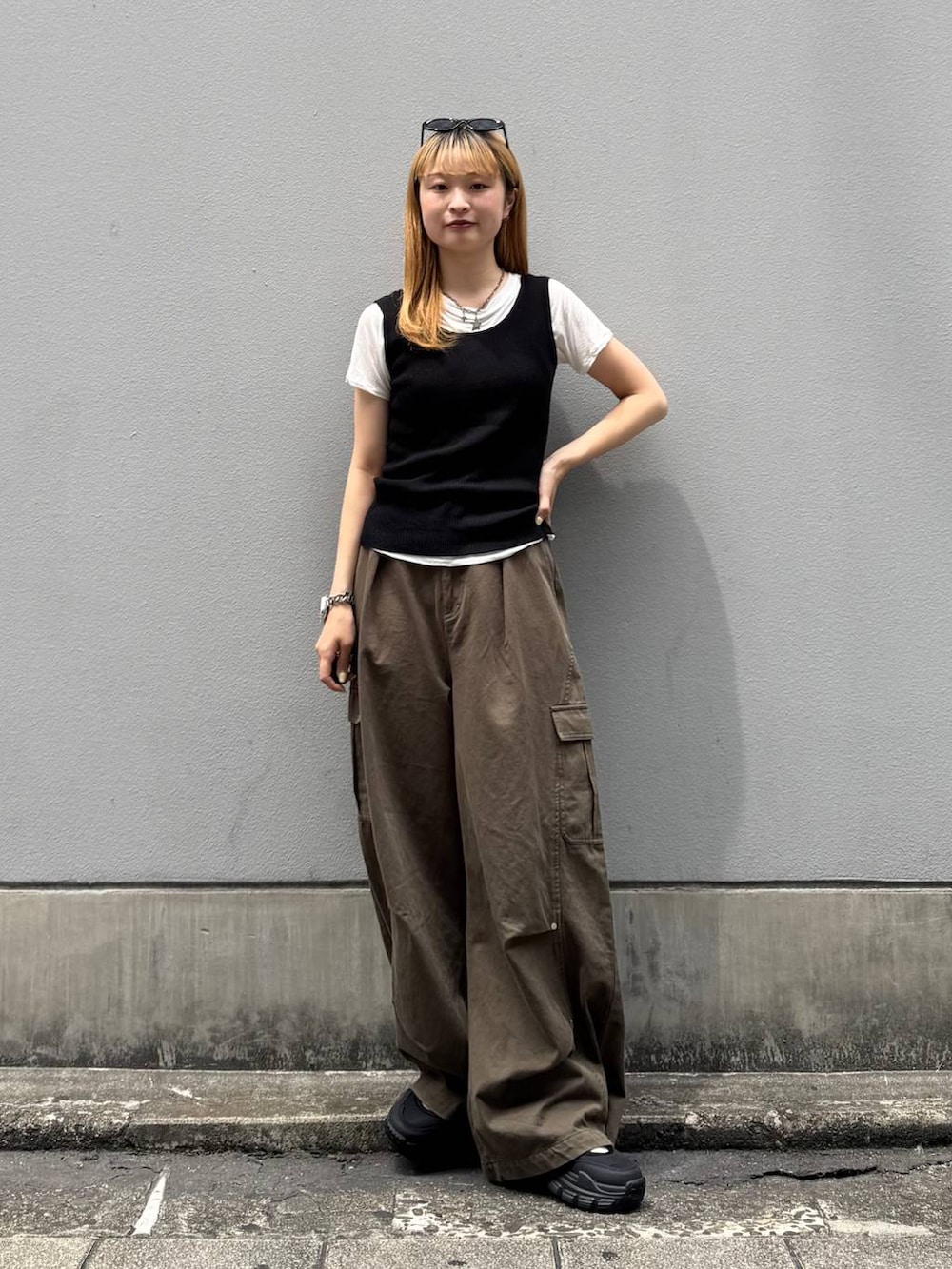 グリーン系のカーゴパンツ、ブラック系のタンクトップ、ブラック系のサンダルを着用したレディースの夏コーディネートの4枚目の写真