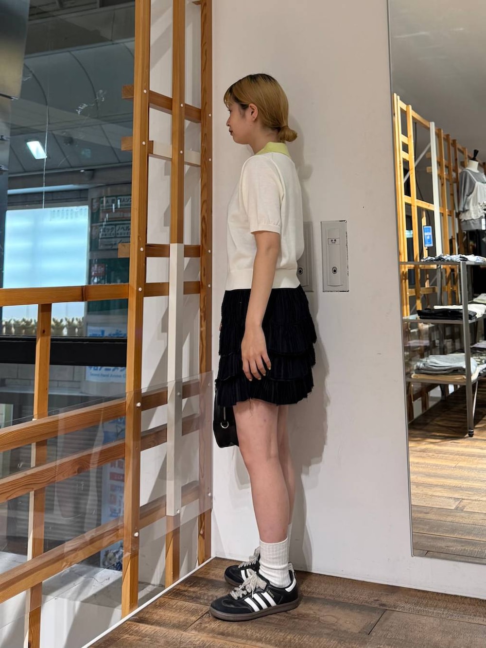 ブラック系のボストンバッグ、ブラック系のスカート、ホワイト系のポロシャツを着用したレディースの夏コーディネートの4枚目の写真